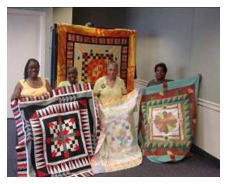 Members of Quilters of the Round Table displaying their work. Image source: qrtphilly.com