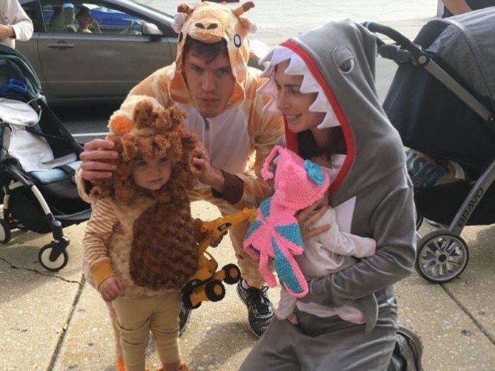caregivers in onesies trick-or-treating with child in lion's costume