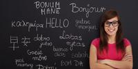 Woman standing at chalkboard with multiple phrases in multiple languages written on it