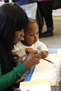 A family uses ink to paint a scroll after a lesson from the Philadelphia Zoo and the Philadelphia Museum of Art.