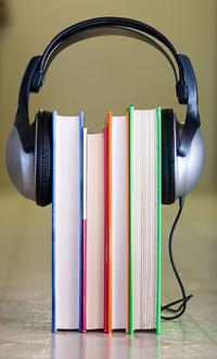 stack of books between a pair of headphones